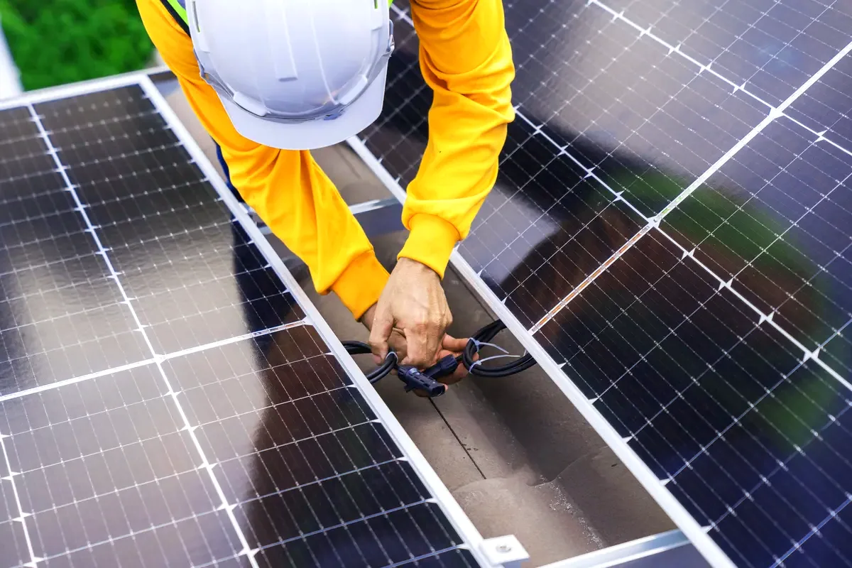 Técnico conectando el cableado de los paneles solares en una cubierta cerca de Hospitalet