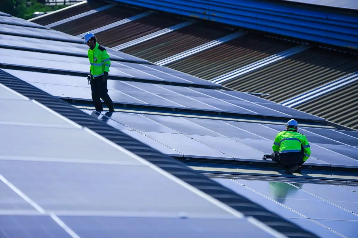 Operarios montando paneles solares sobre una cubierta de nave industrial en El Prat de Llobregat